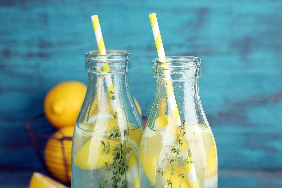 Tasty cool beverage with lemon and thyme, on wooden background